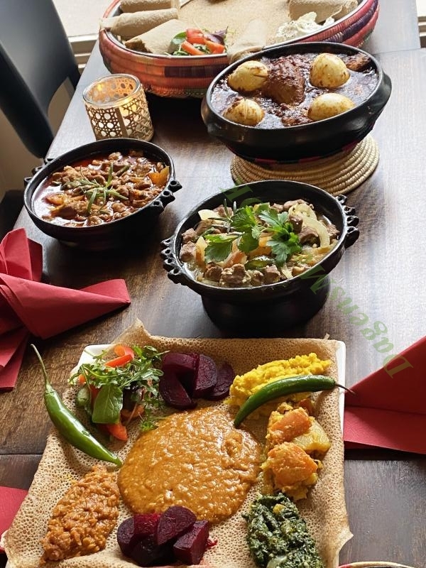 Clay pots of tibsi and stews beside a vegan combination platter